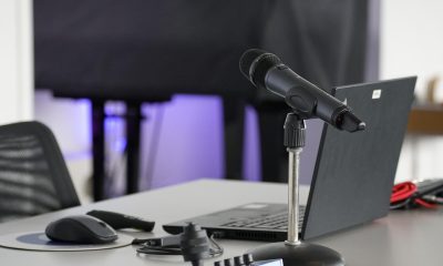 客服人员在耳机麦克风前记录用户反馈内容，桌面摆放着记事本和台灯